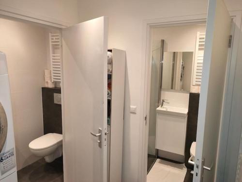 a white bathroom with a toilet and a sink at House with garden in the center close to the sea and Amsterdam in Beverwijk