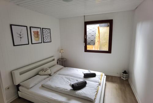 a white bedroom with a bed with a window at Ferienhaus mit Sauna für romantische Zweisamkeit in Molbergen