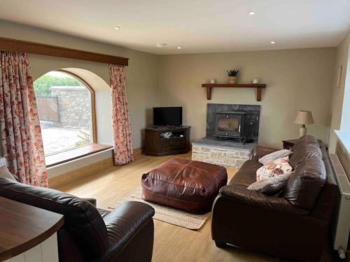 sala de estar con sofá de cuero y chimenea en Tom Rocky’s Farmyard, en Templemore