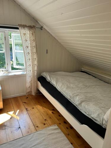 Cama en habitación pequeña con ventana en Sandstad, Lilleby i Trondheim en Trondheim