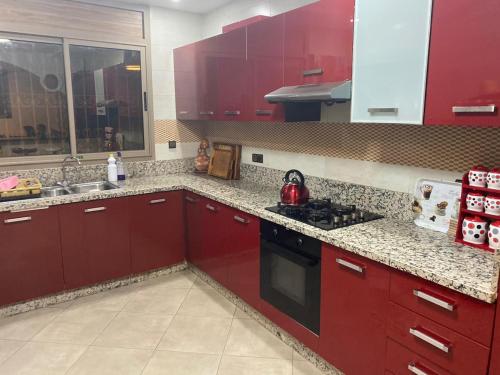uma cozinha com armários vermelhos e um forno com placa de fogão em أكادير ايت ملول em Ait Melloul