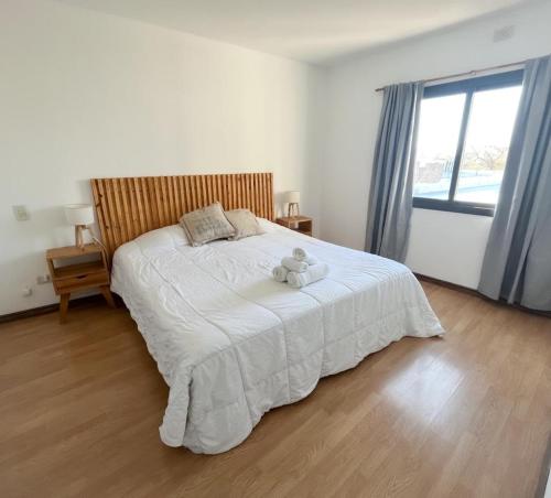 Un dormitorio con una cama blanca con un osito de peluche. en Maravilloso ,amplío, gran ubicación dpto nuevo en Godoy Cruz