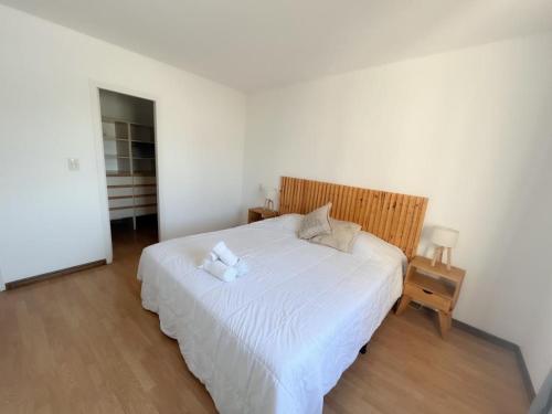 Un dormitorio con una cama blanca con un osito de peluche. en Maravilloso ,amplío, gran ubicación dpto nuevo en Godoy Cruz