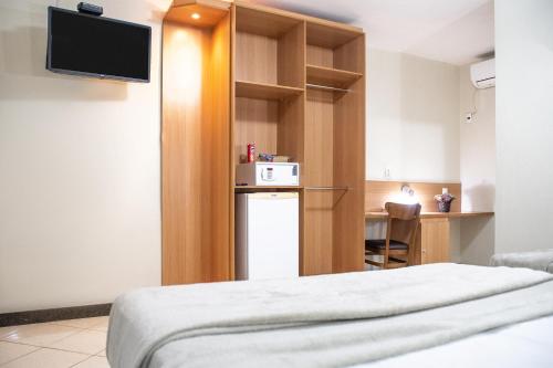 a room with a bed and a small kitchen at Hotel Cravo e Canela in Campos dos Goytacazes
