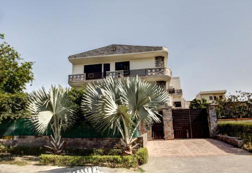 a house with two palm trees in front of it at OYO Home Spacious Studio Sector 21-a Faridabad in Faridabad