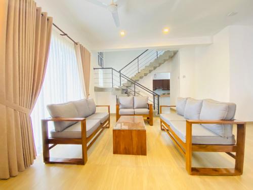 a living room with two chairs and a staircase at Srimadis Villa near Airport - Negombo in Negombo
