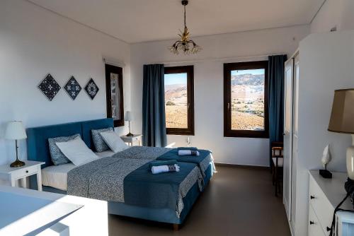 a bedroom with a blue bed and two windows at Seaview Villa in Tavari