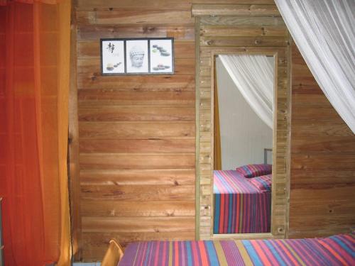 a bedroom with a mirror in a wooden wall at Vacances Bien Etre Guadeloupe in Bouillante