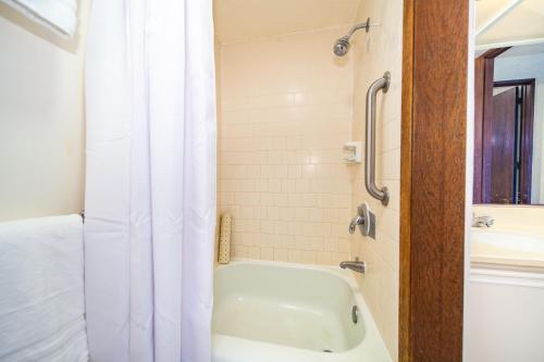 a bathroom with a white tub and a shower curtain at Papakea E406 in Kahana