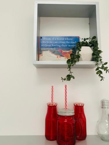 two red jars sitting on a counter with a shelf at Station House in Ballina