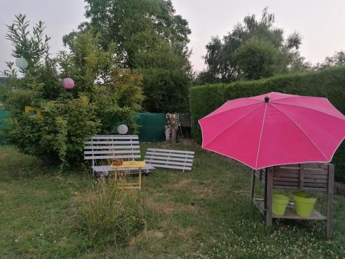 a pink umbrella sitting in a yard with two benches at Chambre au coeur de la Sologne in Romorantin