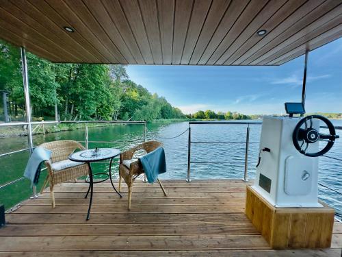 a dock with a table and chairs on a boat at Domki na wodzie - Resort 36 Houseboats in Giżycko