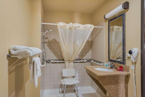 uma casa de banho com um lavatório e um chuveiro com uma cadeira. em SureStay Plus Hotel by Best Western Silver City em Silver City