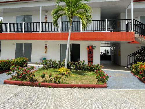 un edificio con una palmera y flores en un patio en Hotel Mar de Corales By CAJASAI, en San Andrés