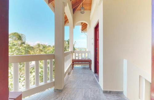 a porch with a red door and a bench at Sandy Feet Beach Resort in Placencia Village