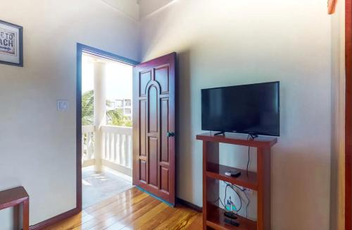 a room with a flat screen tv and a door at Sandy Feet Beach Resort in Placencia Village