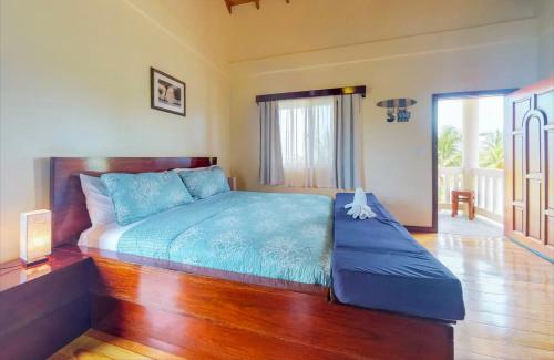 a bedroom with a bed with blue sheets and a wooden floor at Sandy Feet Beach Resort in Placencia Village