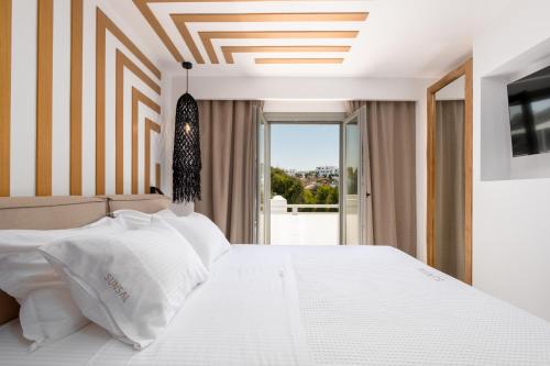 a bedroom with a white bed and a window at SunSal Luxury Studios - Sky in Naousa