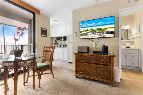 a kitchen and dining room with a table and a television at Noelani 213 in Kahana