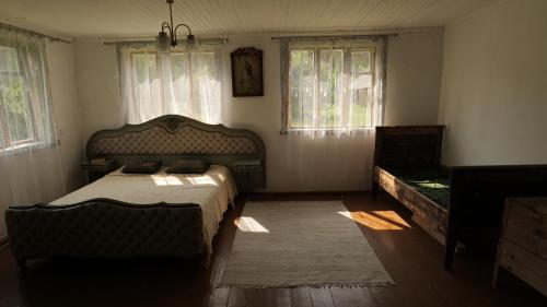 ein Schlafzimmer mit einem Bett und zwei Fenstern in der Unterkunft Inn Kunai in Anykščiai