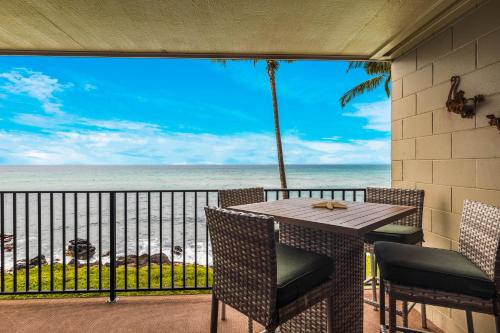 Noelani 206 في Kapalua-West Maui Airport: طاولة وكراسي على شرفة مطلة على الشاطئ