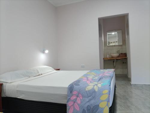 a bedroom with a bed and a bathroom with a sink at Hotel Village del Sol in Puerto Iguazú
