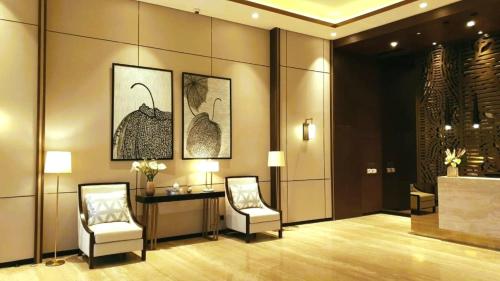 a lobby with two chairs and a table and paintings at Embarcadero Suite Apartment by Novi McKenzie in Pondokaren