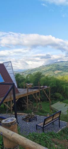 a wooden deck with a table and benches on a hill at Glamping Villa Gilma in Sevilla