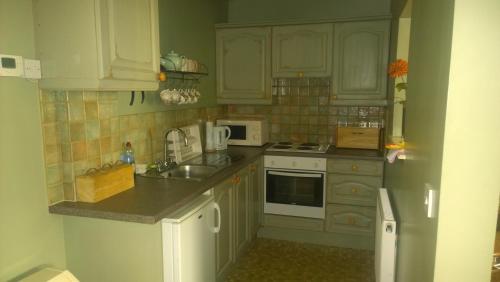 a kitchen with white cabinets and a sink at Fern Farm Cottages in Buxton
