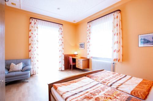 1 dormitorio con paredes de color naranja, 1 cama y 1 sofá en Gästehaus Mittmann, en Bad Kissingen