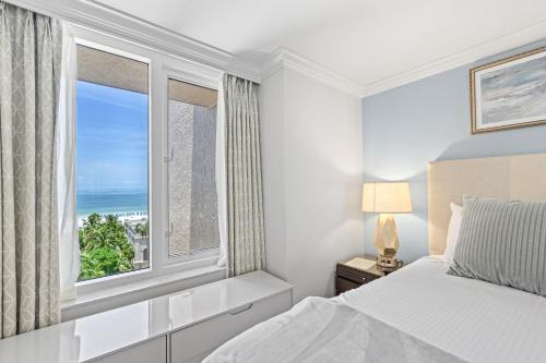 a bedroom with a bed and a window with the ocean at Seashells and Sunshine Marco Beach Ocean Resort 1105 in Marco Island