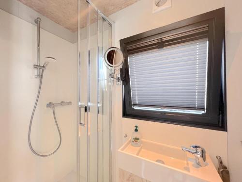 een badkamer met een douche, een wastafel en een raam bij Jopies Houseboat in Maasbommel
