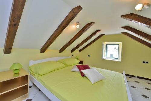 zielone łóżko w pokoju z drewnianymi belkami stropowymi w obiekcie Apartments Carpe Diem w mieście Novigrad