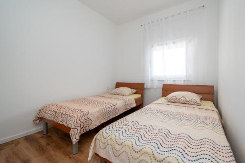 two twin beds in a room with a window at Apartments with a parking space Povljana, Pag - 11516 in Povljana