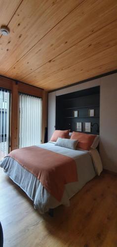 um quarto com uma cama grande e um tecto em madeira em Hermoso monoambiente de diseño único, con patio, en el centro de SMA. 4v5 em San Martín de los Andes