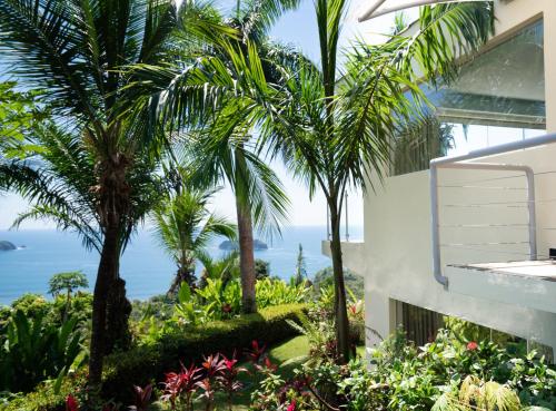 a view of the ocean from a house with palm trees at Hotel La Mariposa in Manuel Antonio