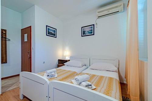 biała sypialnia z 2 łóżkami i ręcznikami w obiekcie Apartments and rooms with WiFi Lastovo - 13678 w mieście Lastovo