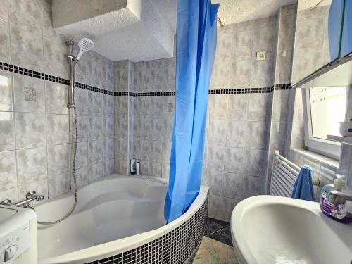 un bagno con vasca, lavandino e tenda doccia blu di Wohnreich Ulm Zentral 3er WG a Ulma