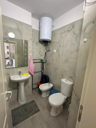 uma casa de banho com 2 WC, um lavatório e um espelho. em Beach front Durres 2 em Durrës