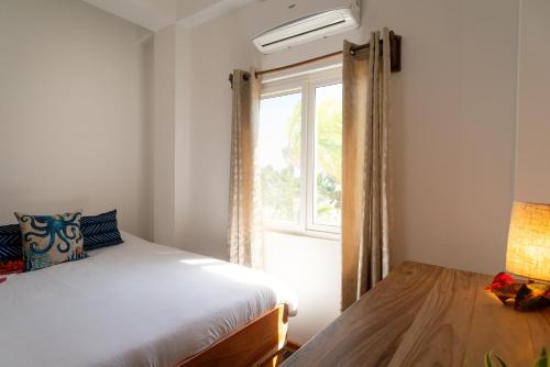 a bedroom with a bed and a window at Sandy Feet Beach Resort in Placencia Village