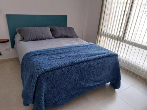 Una cama con una manta azul en un dormitorio en Sierras de Paz en Tandil