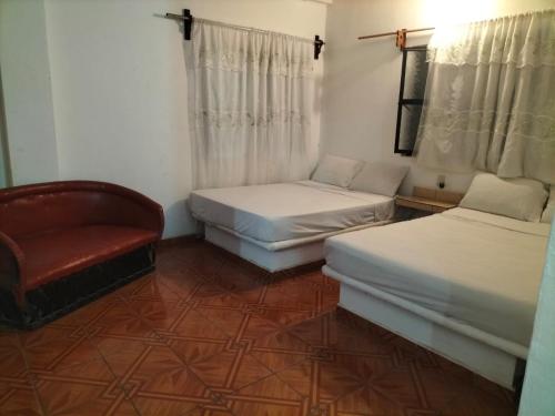 a room with two beds and a chair in it at Casa las cabras in La Peñita de Jaltemba