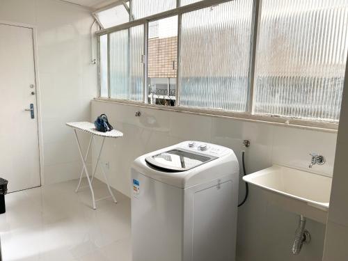 a white bathroom with a washing machine and a sink at Apartamento em Belo Horizonte in Belo Horizonte