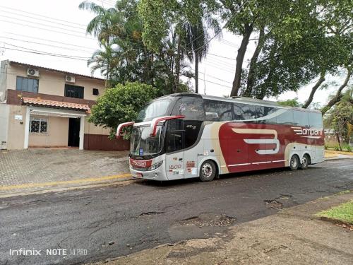 a red and white bus parked in front of a house at Suite Cardoso in Foz do Iguaçu