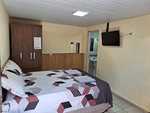 a bedroom with a bed and a tv on the wall at Suite Cardoso in Foz do Iguaçu