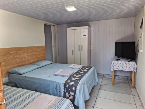 a small bedroom with two beds and a television at Suite Cardoso in Foz do Iguaçu