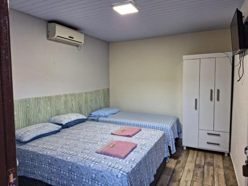 a room with two beds and a cabinet in it at Suite Cardoso in Foz do Iguaçu