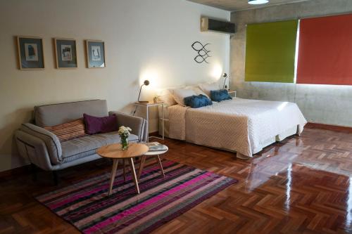 a bedroom with a bed and a couch and a table at Niceto Studio in Buenos Aires