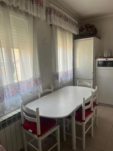 a kitchen with a white table and chairs and a refrigerator at Piso pineda in Monforte de Lemos
