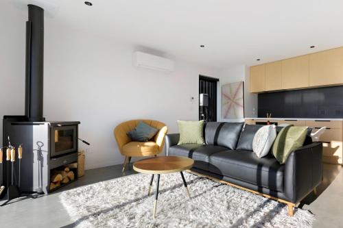 a living room with a black leather couch and a fireplace at Camp Cardrona Apartments in Cardrona
